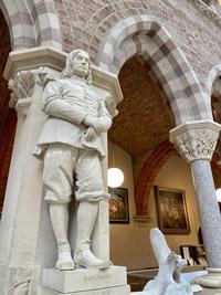 statue of man next to arch of old building pillars